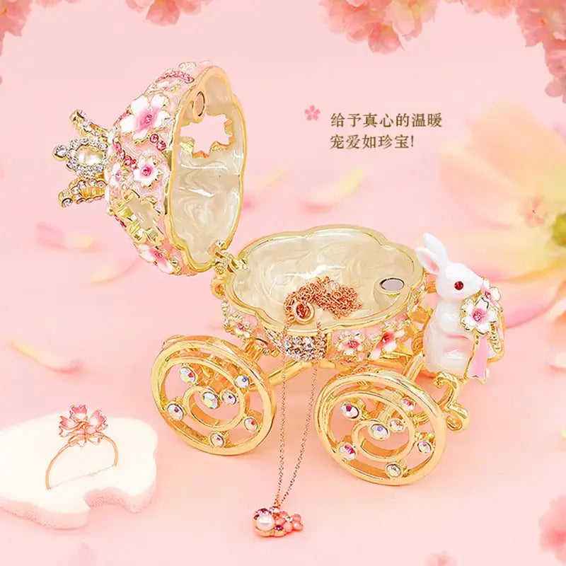 Pink and gold princess carriage jewelry trinket box adorned with rhinestones floral patterns and white rabbit figurine