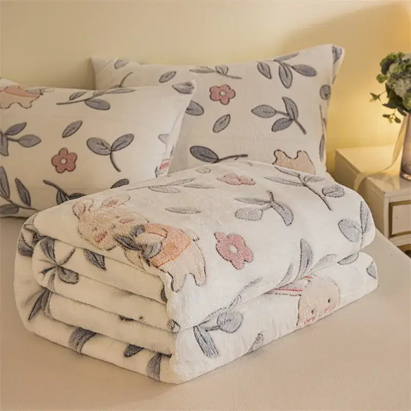 A plush white fleece blanket with embroidered pink flowers gray leaves and a beige bunny in double sided plaid design