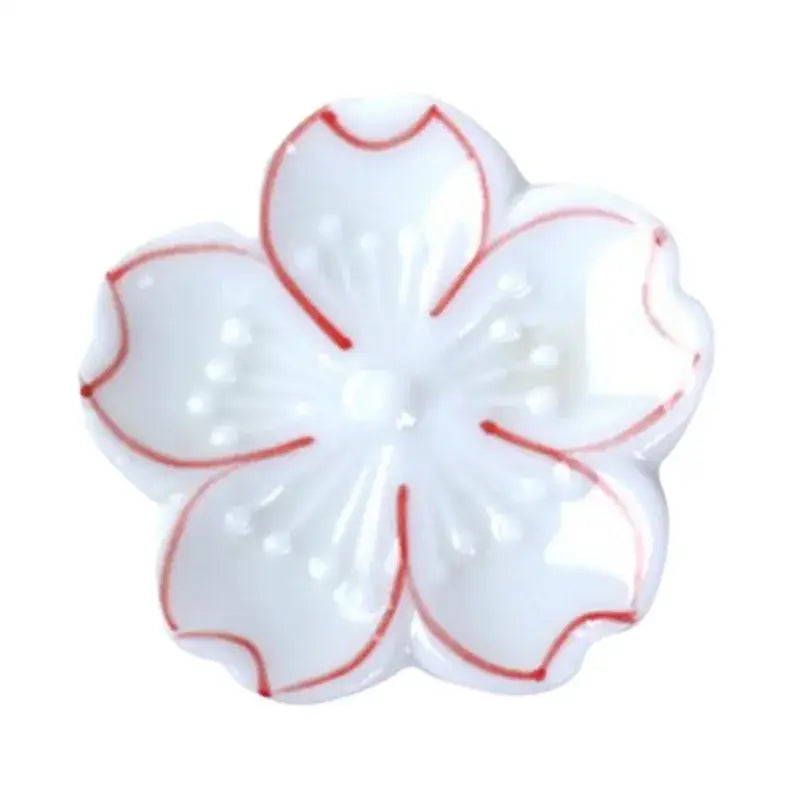 White ceramic cherry blossom dish with red petal outlines pink and green decorbites ceramic sakura chopstick rest