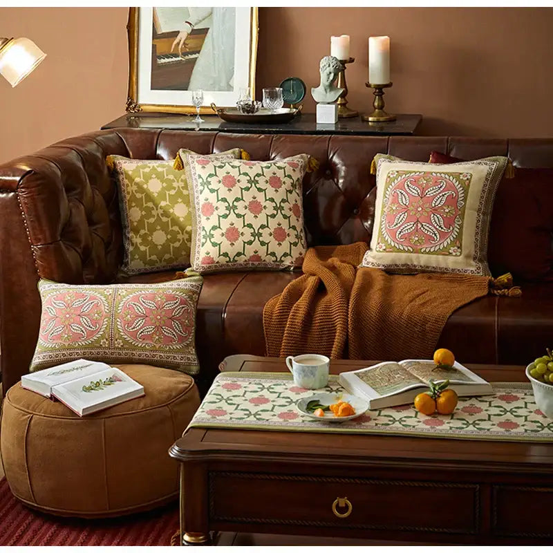 Four decorative throw pillows with pink and green datura flowers print embroidery on brown leather sofa for living room decor