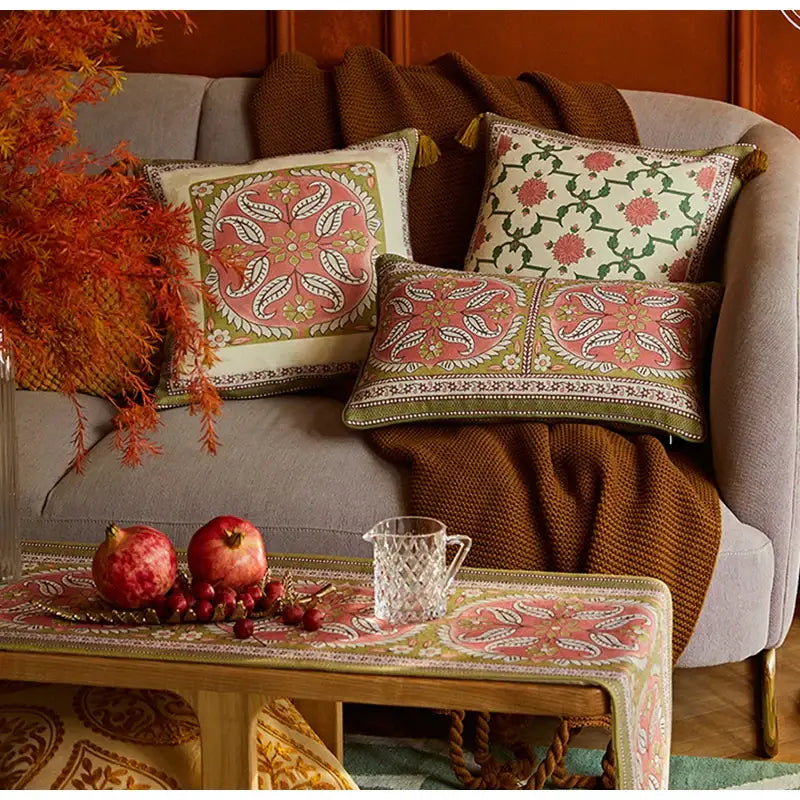 Patterned pink and green datura flowers print cushion covers with embroidered floral designs on a gray sofa