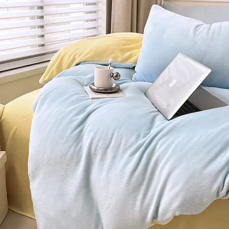Light blue plush blanket draped over bed in pink and green milk velvet bedding set for winter comfort and style