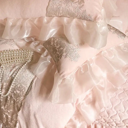 A blush pink satin pillow sham with silver decorbites french lace ruffles from a bedding set for bedroom decor
