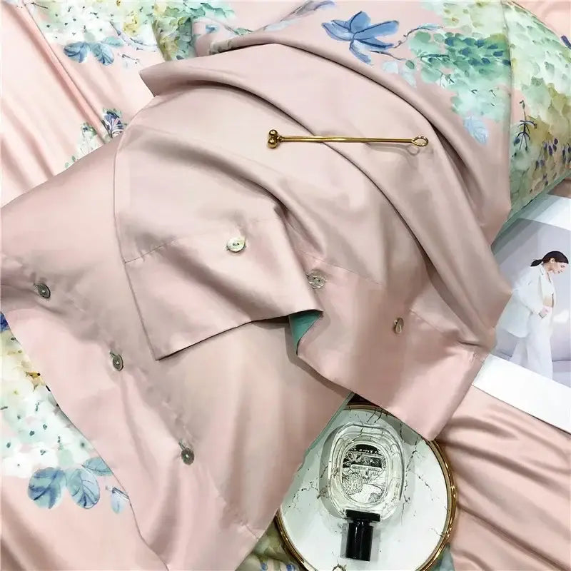 Pink satin pillowcase with floral embroidery and gold safety pin as part of a pink and teal egyptian cotton bedding set