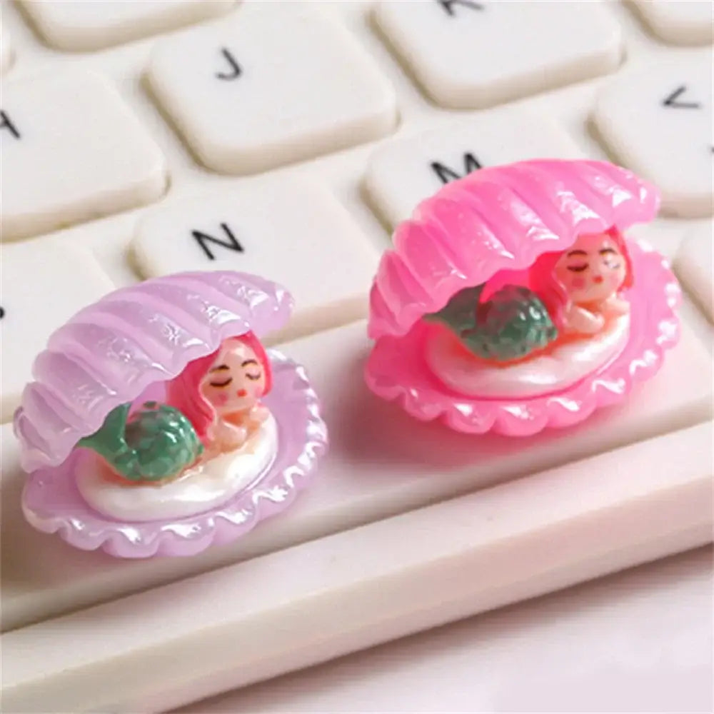 Pink and lavender plastic clamshell keycaps with green-tailed mermaid figurines from decorbites colorful plated seashells decor