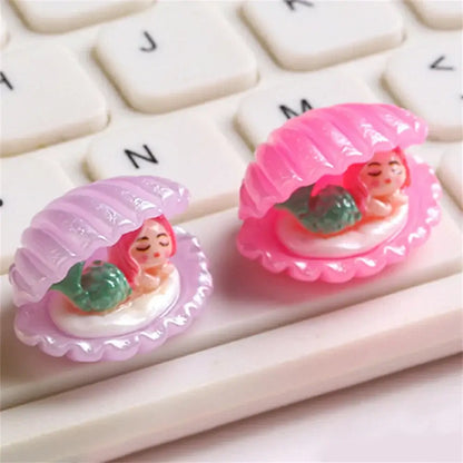 Pink and lavender plastic clamshell keycaps with green-tailed mermaid figurines from decorbites colorful plated seashells decor