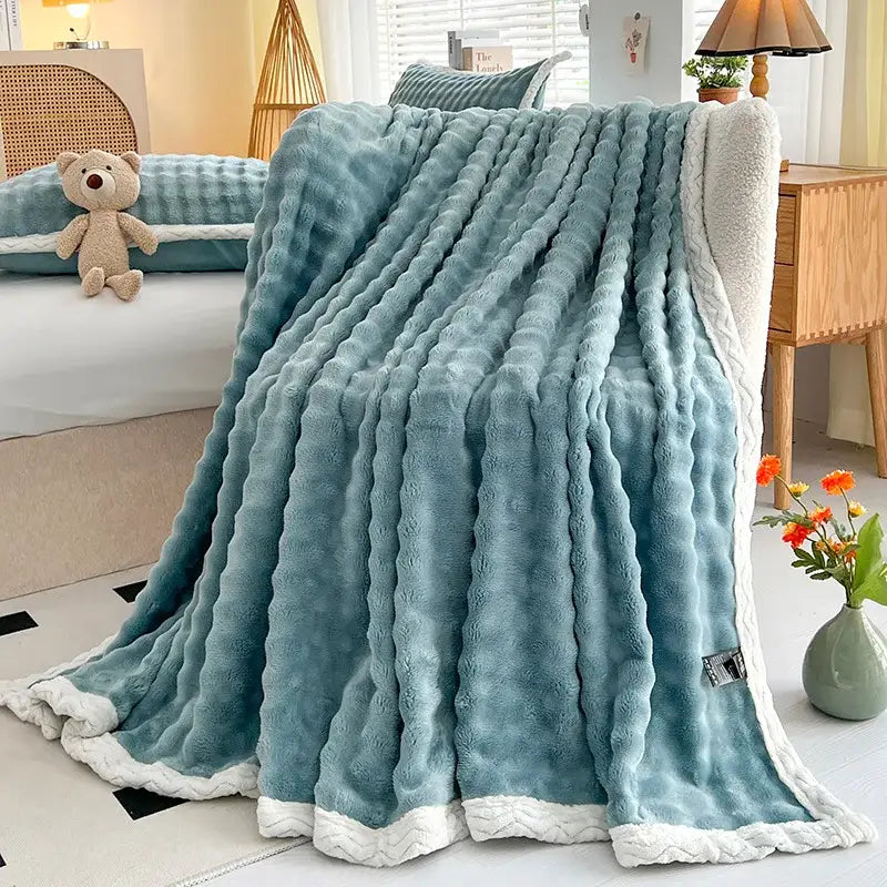 A teal plush throw blanket with ribbed texture and white fleece trim from decorbites cozy faux rabbit fur collection