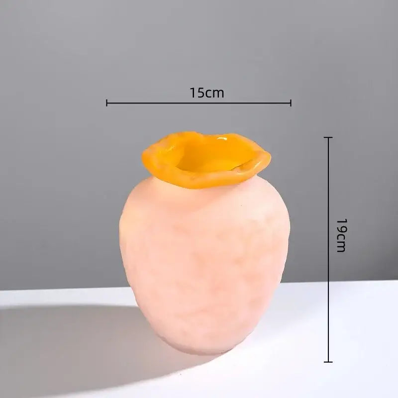 A peach-colored frosted glass vase with a vibrant yellow lip-like rim for decorbites colorful frosted living room decor