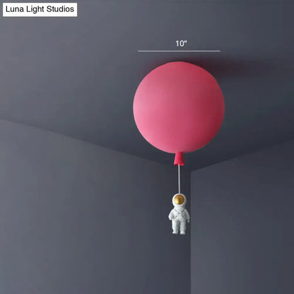 Pink astronaut ceiling lamp featuring a pink balloon-shaped acrylic pendant light with a white astronaut figurine for kids bedroom
