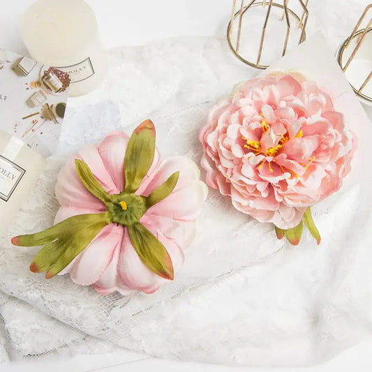 Pink big peony headwear artificial flowers with layered petals and green leaves displayed on lace surface for wedding decoration