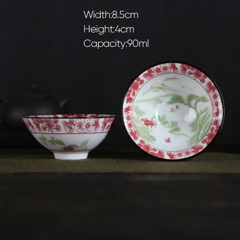 White porcelain hand-painted tea bowl with red green floral and landscape designs and decorative rim decorbites blue