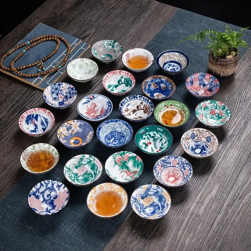 A collection of pink and black floral white porcelain hand-painted tea bowls with vibrant decorbites blue patterns