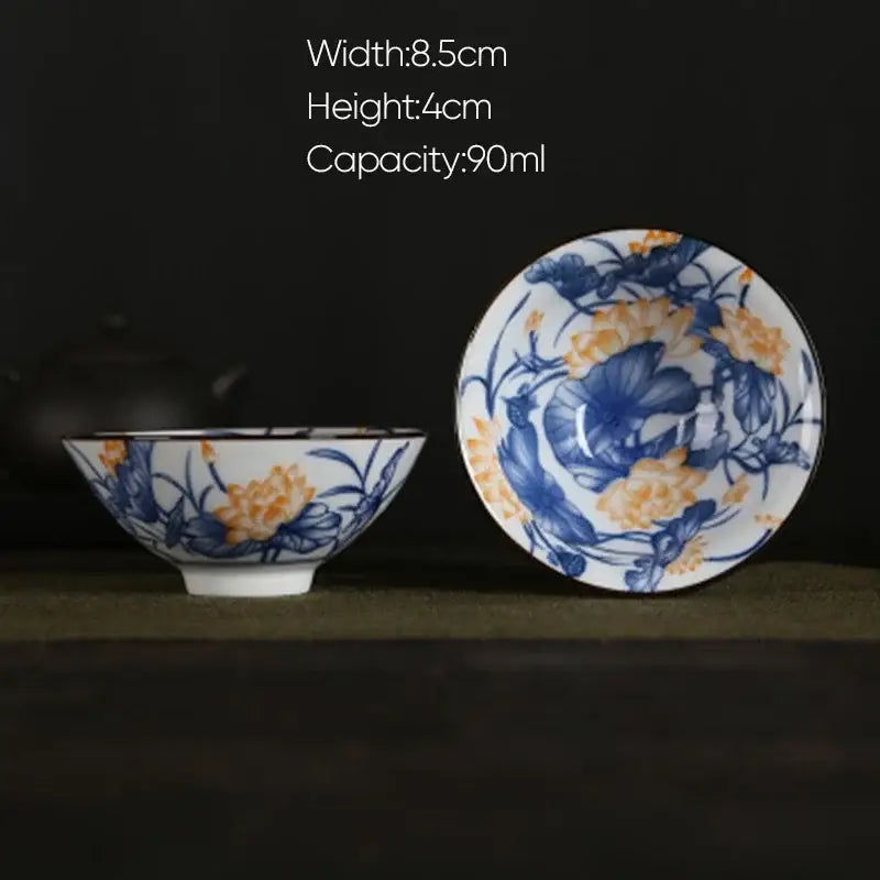 A delicate white porcelain hand-painted tea bowl with blue and orange floral decorbites blue pattern and matching saucer