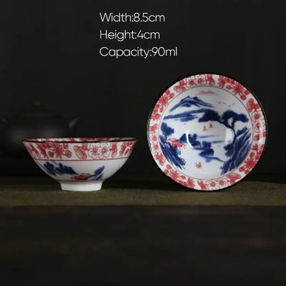 A traditional white porcelain hand-painted tea bowl with blue and red floral and landscape decorbites blue patterns