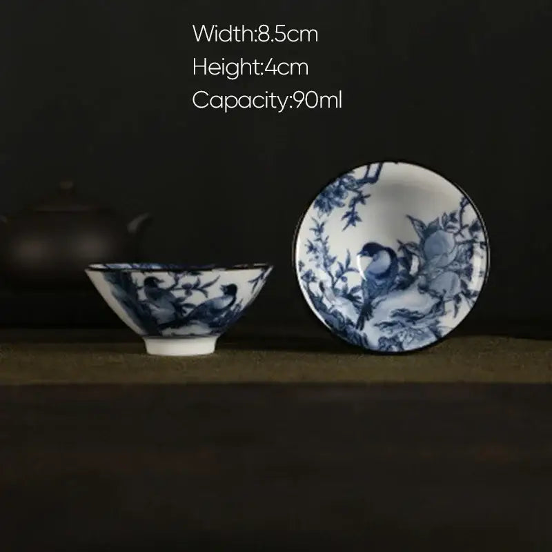 A delicate decorbites blue and white porcelain hand-painted tea bowl with bird and branch designs and matching saucer