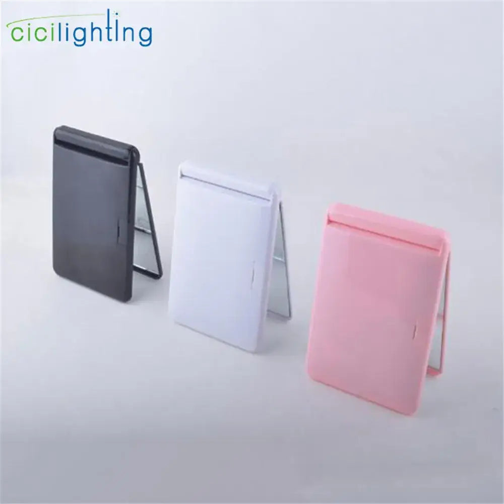 Three foldable led vanity mirror compacts in black white and pink plastic casings for bedroom makeup use