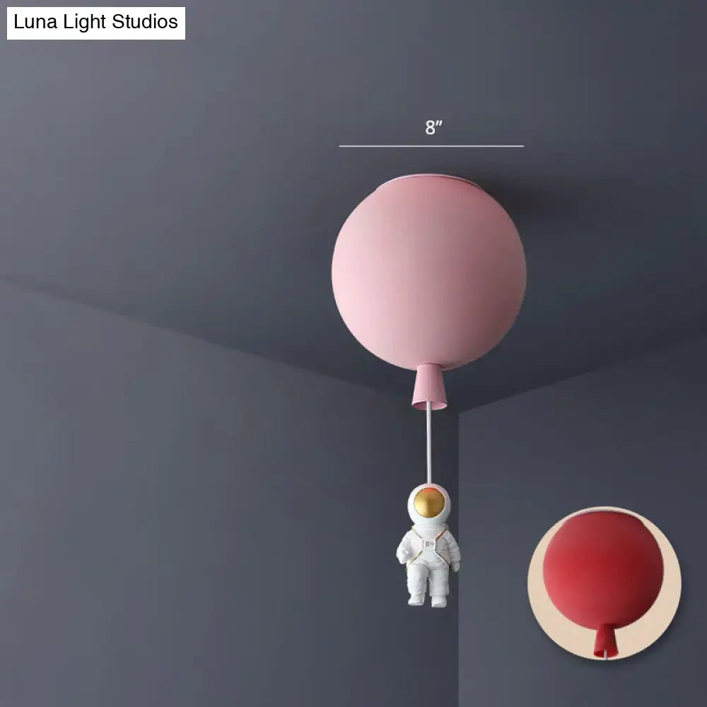 Pink balloon-shaped ceiling lamp with white astronaut figurine hanging below astronaut ceiling lamp for bedrooms
