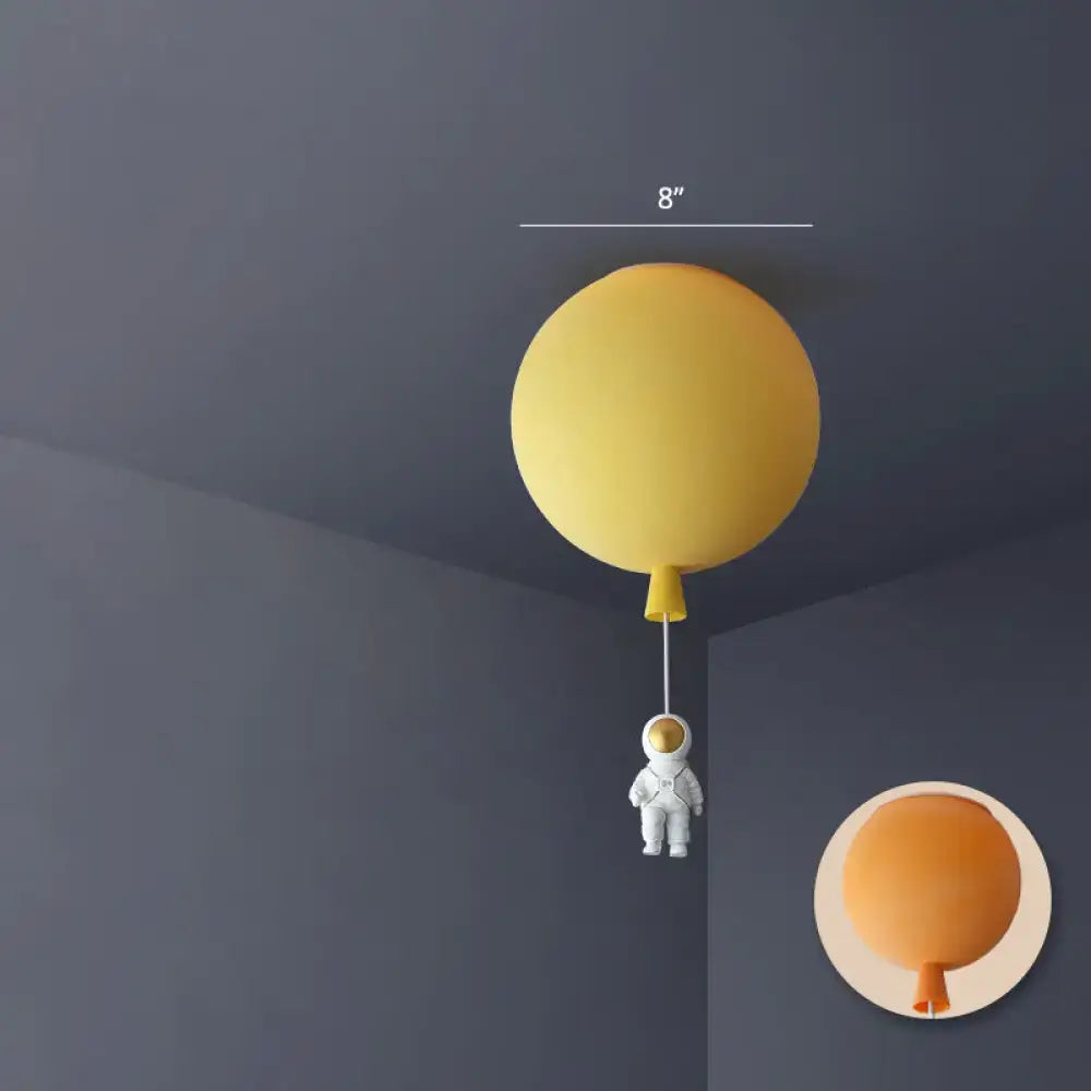 Yellow balloon-shaped ceiling lamp with a miniature astronaut figure hanging below in astronaut ceiling lamp design