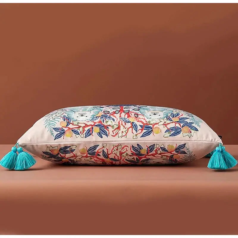 Rectangular cream lumbar pillow cover with blue lion dog embroidered floral and fruit patterns and turquoise tassels