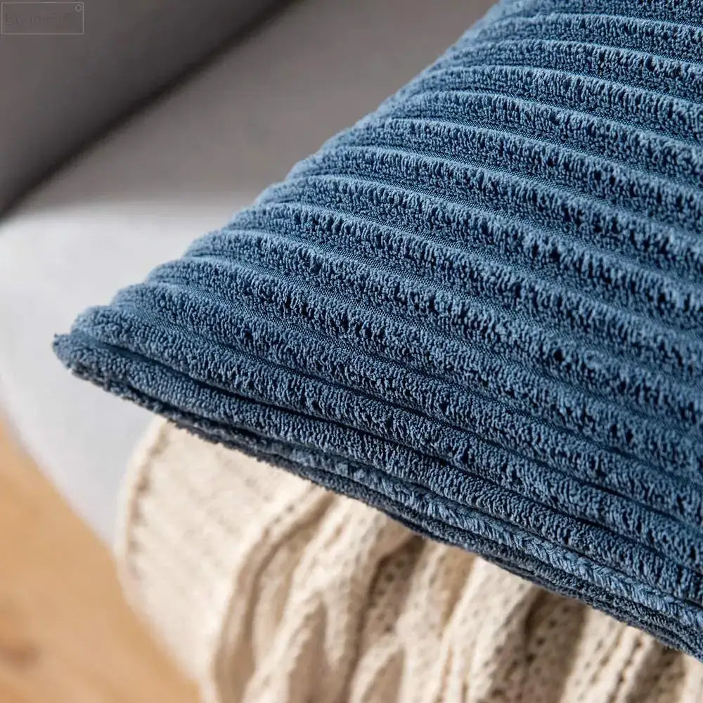 A plush deep blue decorbites corduroy pillow cover featuring soft textured vertical ridges for living room decor