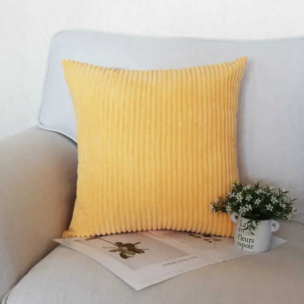 A vibrant yellow decorbites corduroy pillow with soft ribbed texture on light gray sofa for living room decor