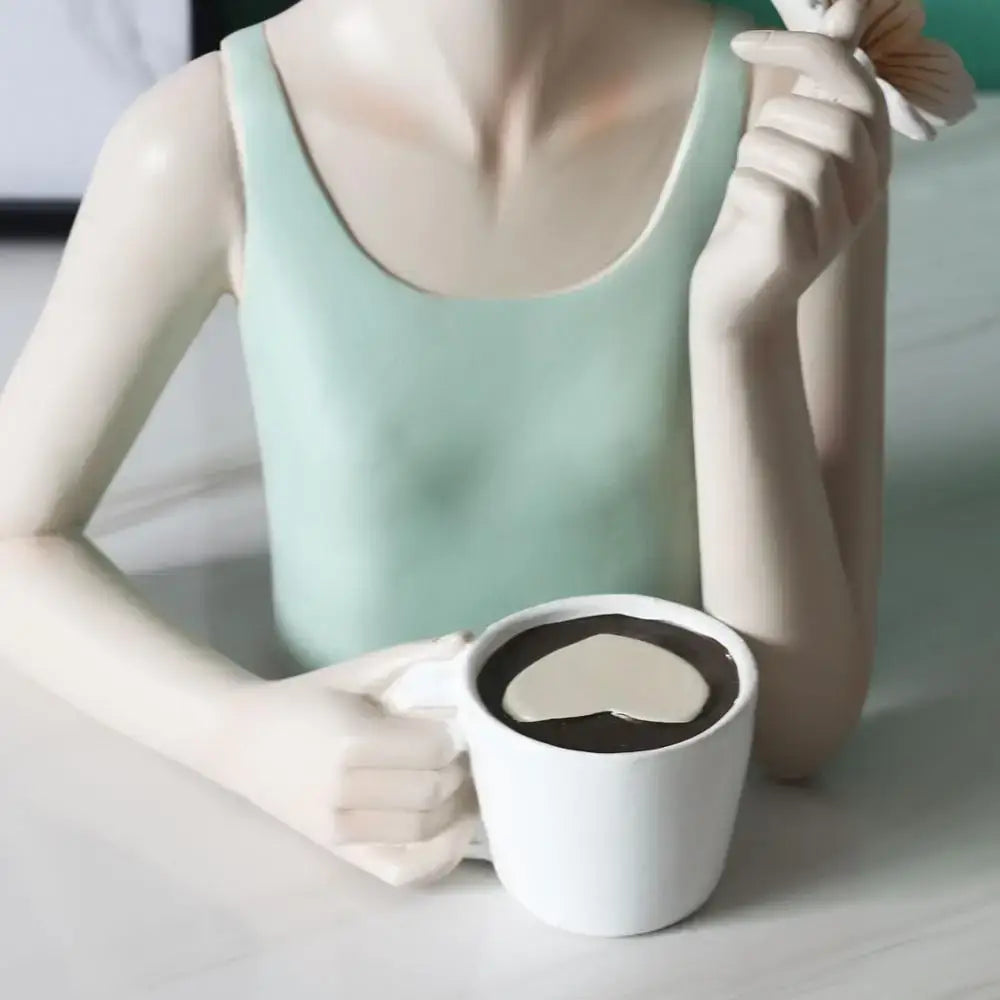 A ceramic figurine of a woman in a mint green tank top holding a mug with heart cream swirl on a pink butterfly fairy resin tray decorbites butterfly fairy decor