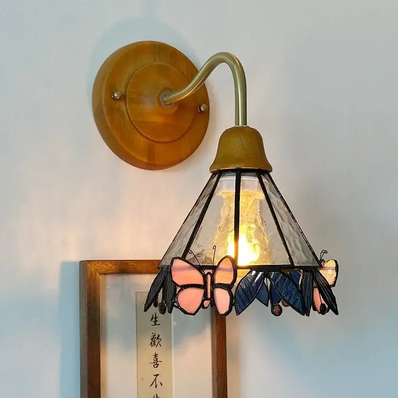 A warm-toned wooden pink butterfly glass led wall sconce with brass arm and stained glass shade decorbites glass led