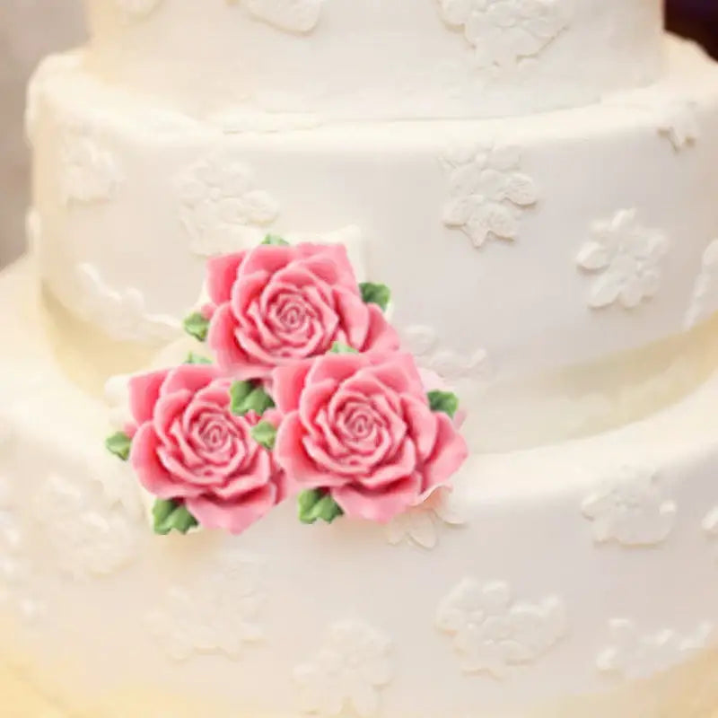 A three-tiered white wedding cake decorated with pink sugar roses made using pink butterfly silicone fondant mold decorbites butterfly silicone