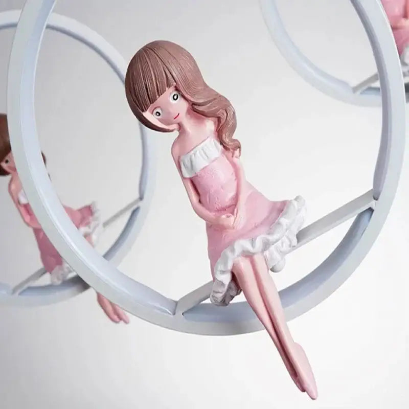 Pink resin figurine of girl in off-shoulder dress with white ruffles seated in circular frame for decorbites cartoon princess kids chandelier