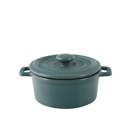 A sleek matte teal enameled cast iron cocotte with lid and handles paired with pink decorbites ceramic mini soup bowl