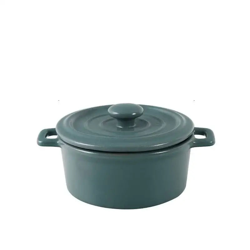 A sleek matte teal enameled cast iron cocotte with lid and handles paired with pink decorbites ceramic mini soup bowl