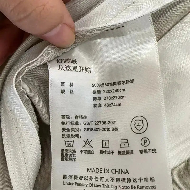 White fabric care label with black chinese text and english details on pink cotton flowers embroidery bedding set made in china