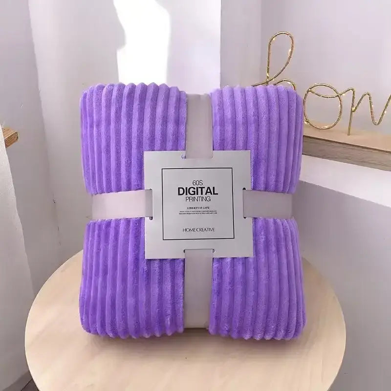 A lavender corduroy throw blanket wrapped with a white ribbon featuring decorbites cozy striped label