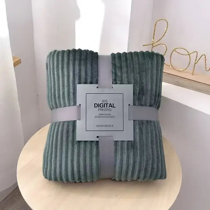 A soft teal-green corduroy throw blanket wrapped with gray ribbons featuring a white label for decorbites cozy striped flannel fleece decor