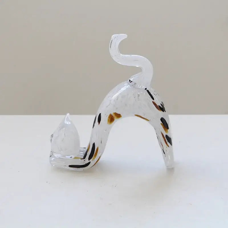A translucent pink crystal cat figurine with black and brown spots arched in a living room decorbites crystal cat design