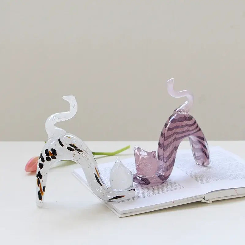 Two translucent glass cat figurines with black orange spots and purple stripes in a pink crystal cat living room decorbites statue