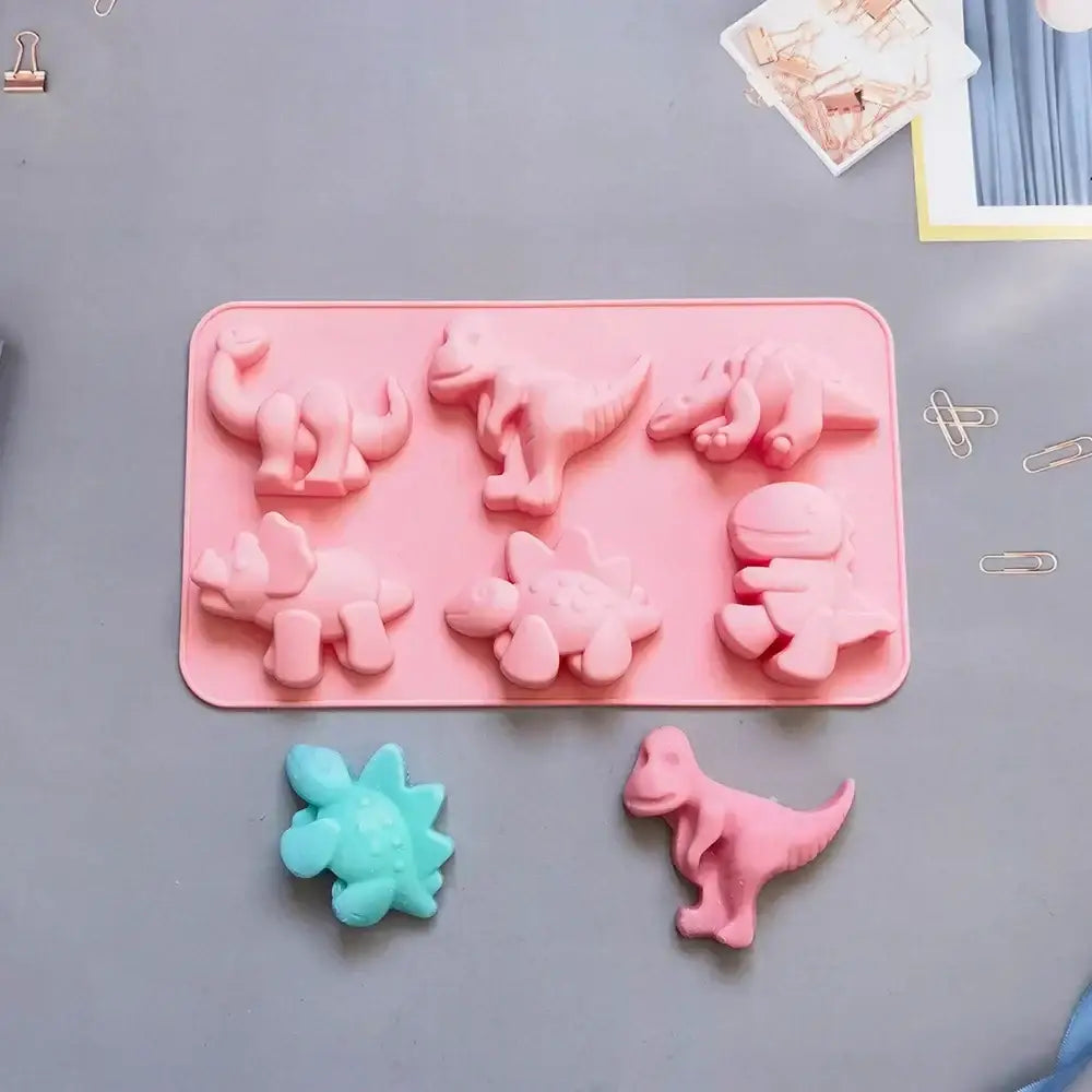 Pink dino silicone cake mold with six cavities and two finished dinosaur shapes for kitchen baking use
