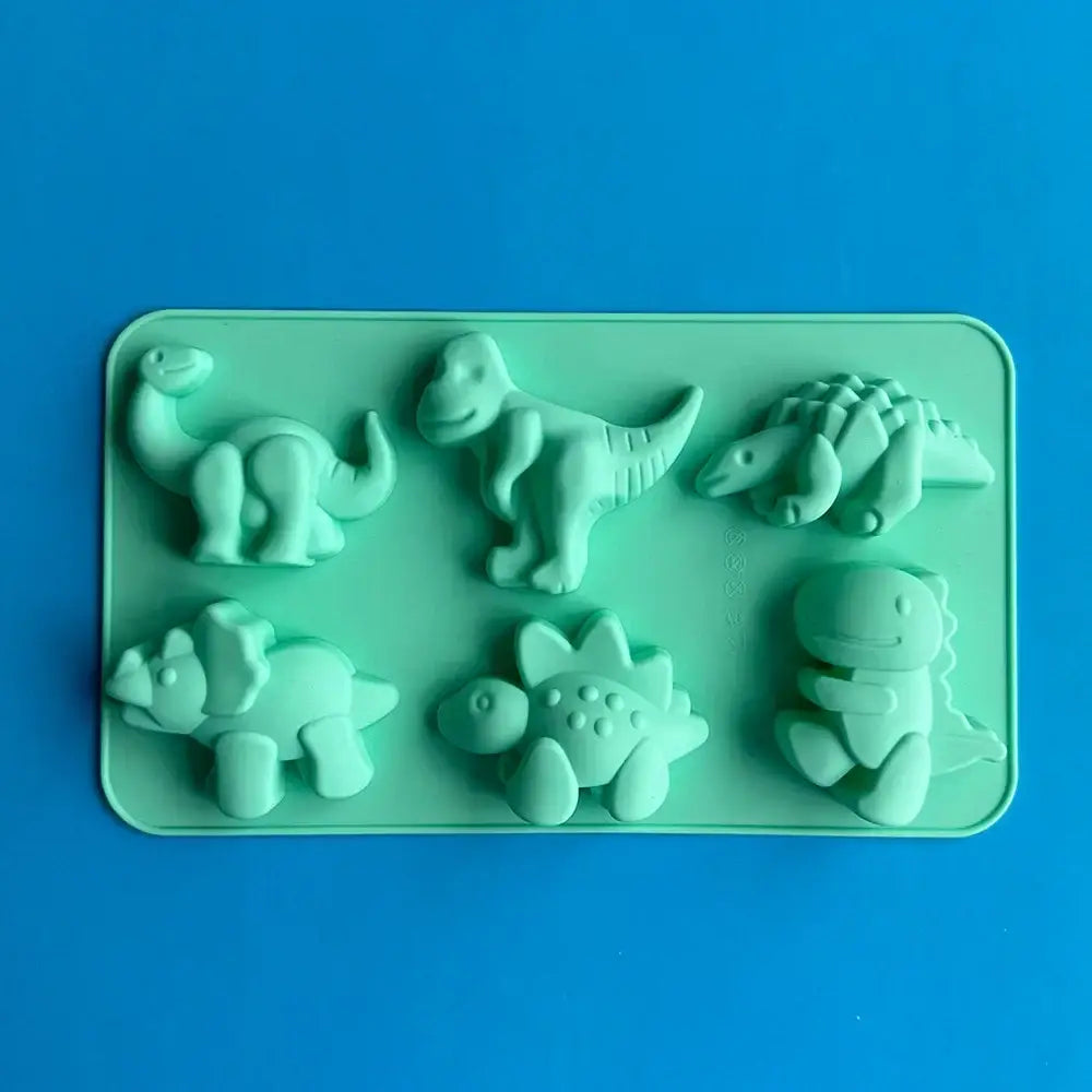 Light green silicone cake mold with six dino silicone shapes for baking in a pink dino silicone cake tray