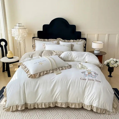 Cream-colored cotton bed skirt set with ruffled edges and embroidered cute little bear design on the duvet