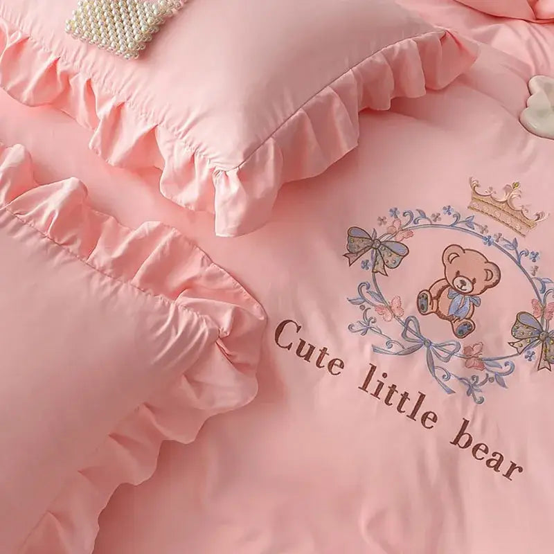 Pink embroidered bear cotton bed skirt set with satin fabric, ruffled edges, and crown-accented bear design