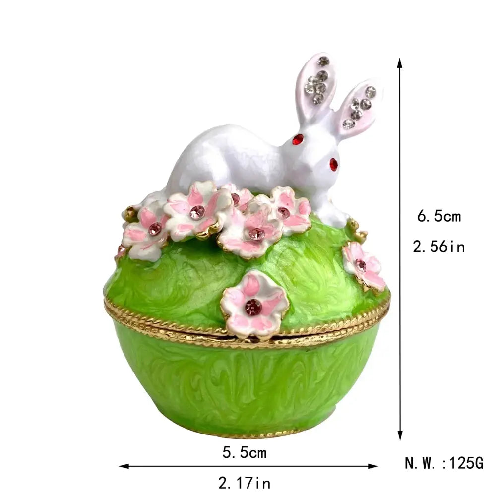 A white rabbit figurine with red gemstone eyes sits atop a pink floral heart jewelry trinket box storage case