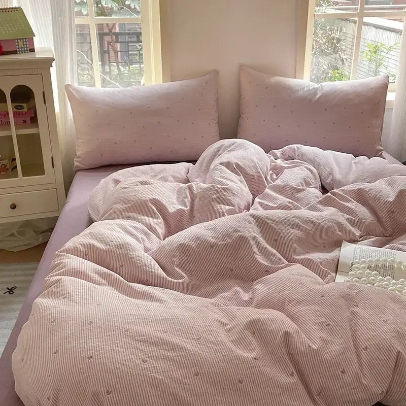 Pink striped duvet cover set with subtle dot pattern paired with pink floral jacquard fitted sheet set soft textured yarn