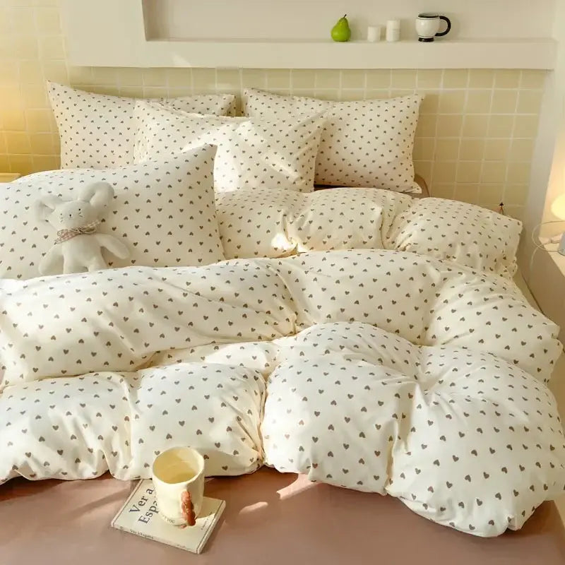 Cream-colored quilted comforter with dark gray hearts paired with pink floral jacquard fitted sheet set for bedroom