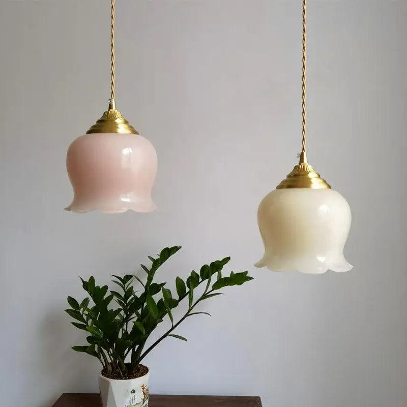 Two delicate pink and cream glass copper led pendant lights suspended by twisted gold-toned chains for kitchen decor