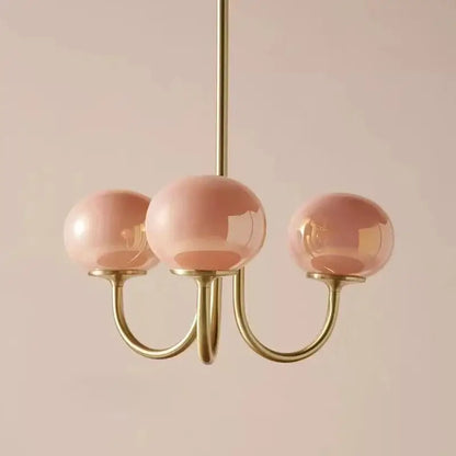 A delicate decorbites designer loft pendant light with soft pink glass globes and polished brass arms for bedroom decor