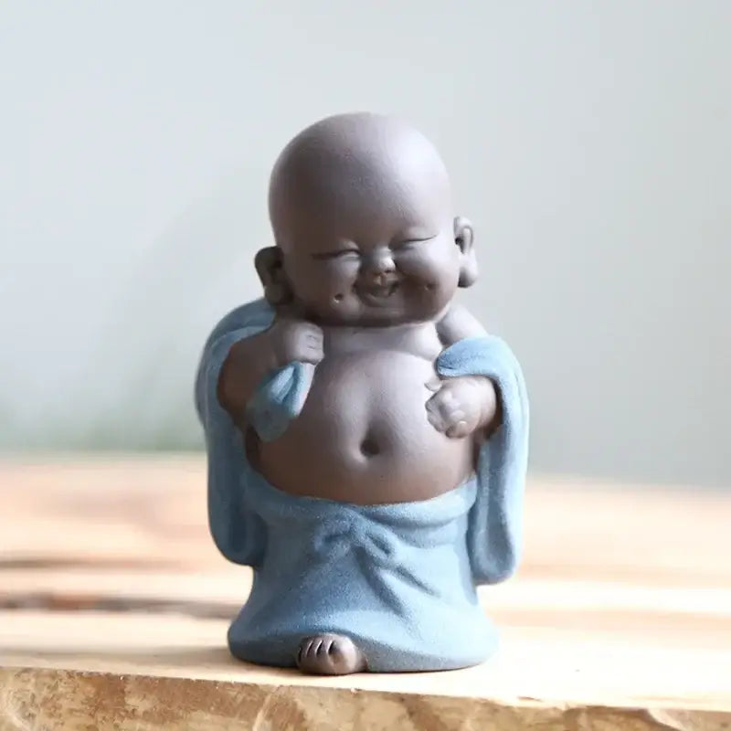 A charming pink and green ceramic maitreya buddha statue tea sculpture with a smiling baby monk in light blue robes
