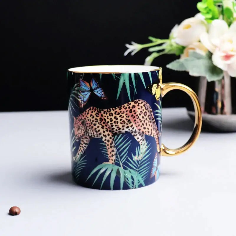 A navy blue ceramic mug with gold rim and handle featuring an illustrated leopard and tropical jungle animals decorbites bone china design