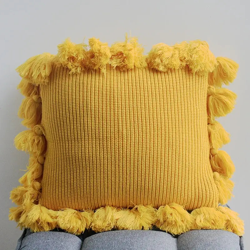 A cozy mustard-yellow decorbites knit cushion cover with fluffy tassel fringe for living room decor