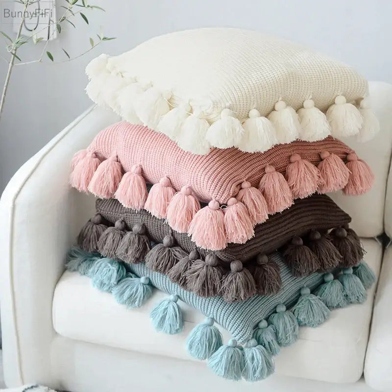 Stack of four decorbites knit cushion covers in cream blush pink muted brown and dusty blue with tassels for living room decor