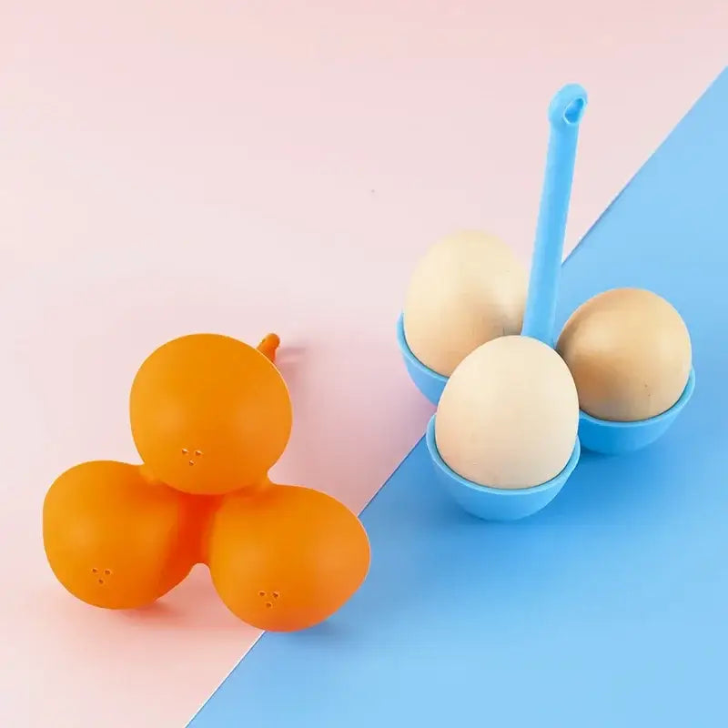 Orange silicone egg steamer tray with three rounded face-like sections and small perforations for kitchen use